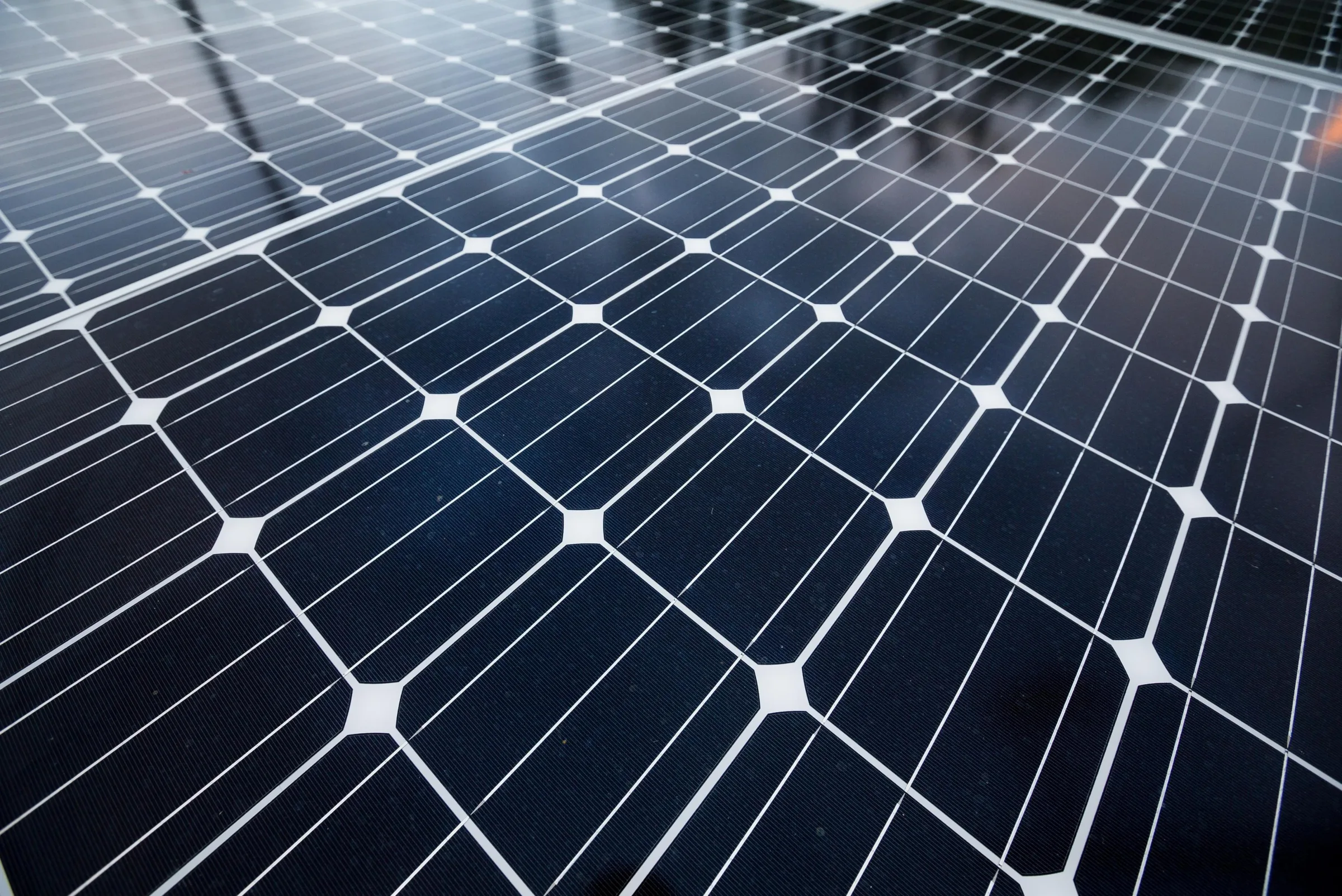 Close-up of solar panel array with dark cells separated by white grid lines, angled perspective view