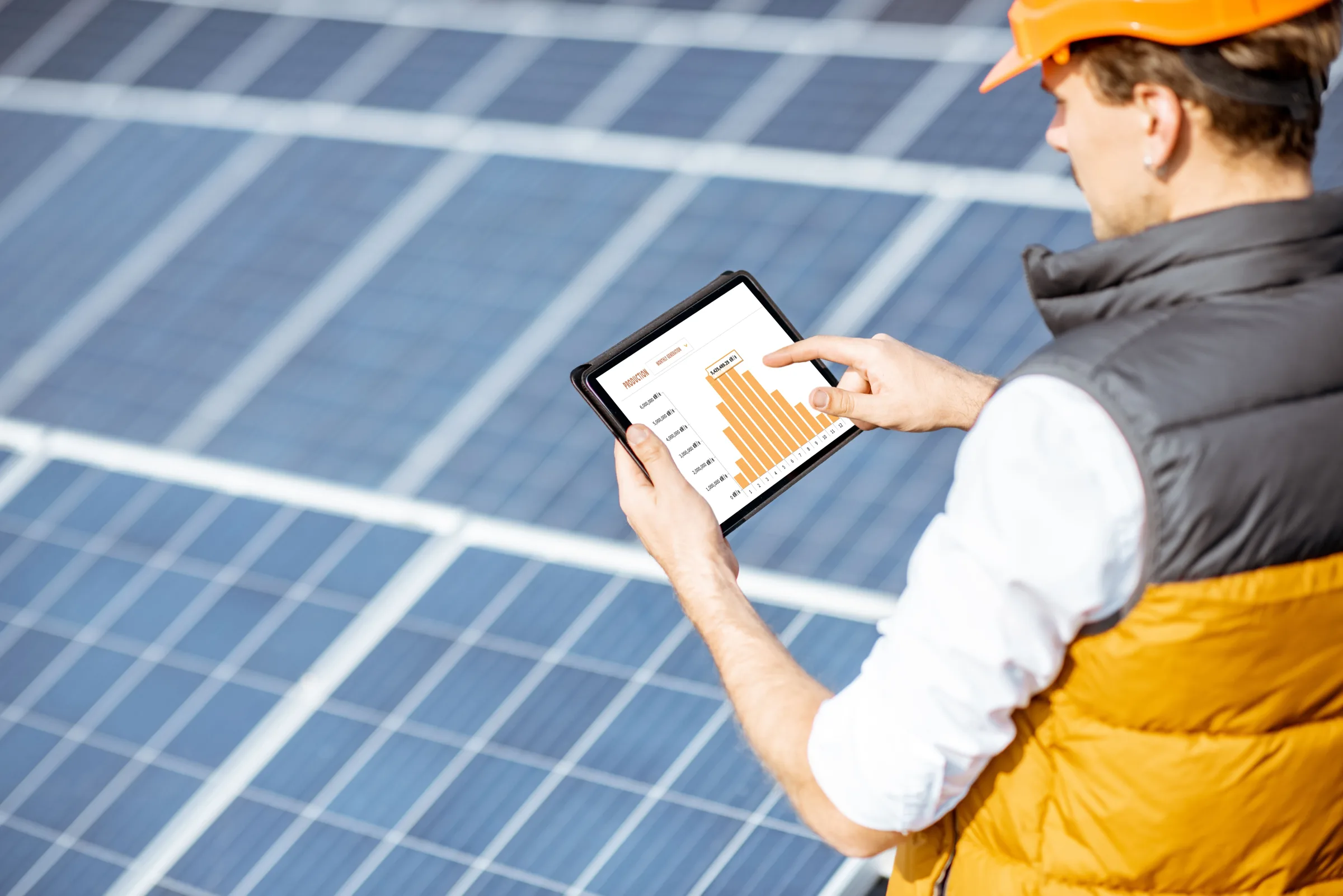 Solar technician reviewing energy production data on tablet at photovoltaic panel installation site