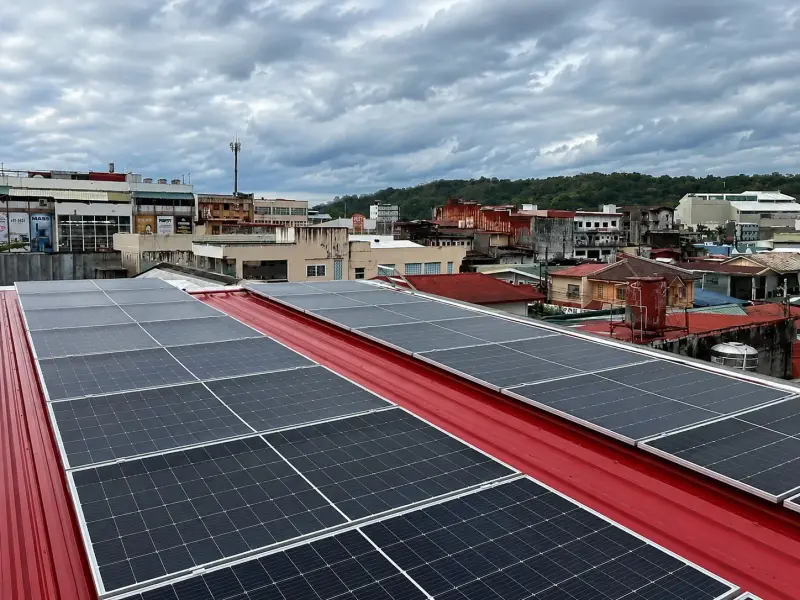Solar panel array installed on industrial rooftop overlooking riverside warehouses and buildings